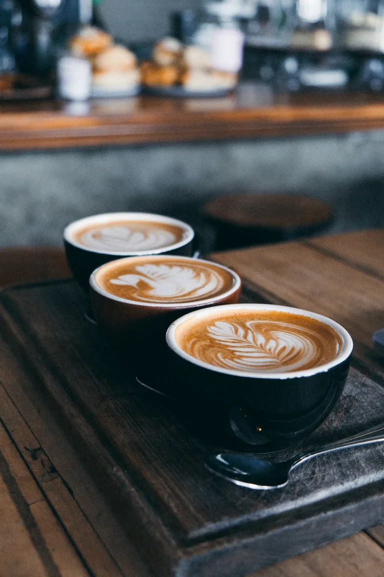 Three cups of coffee on a wooden table in Kalk Bay, photographed by Karabo Mdluli.
